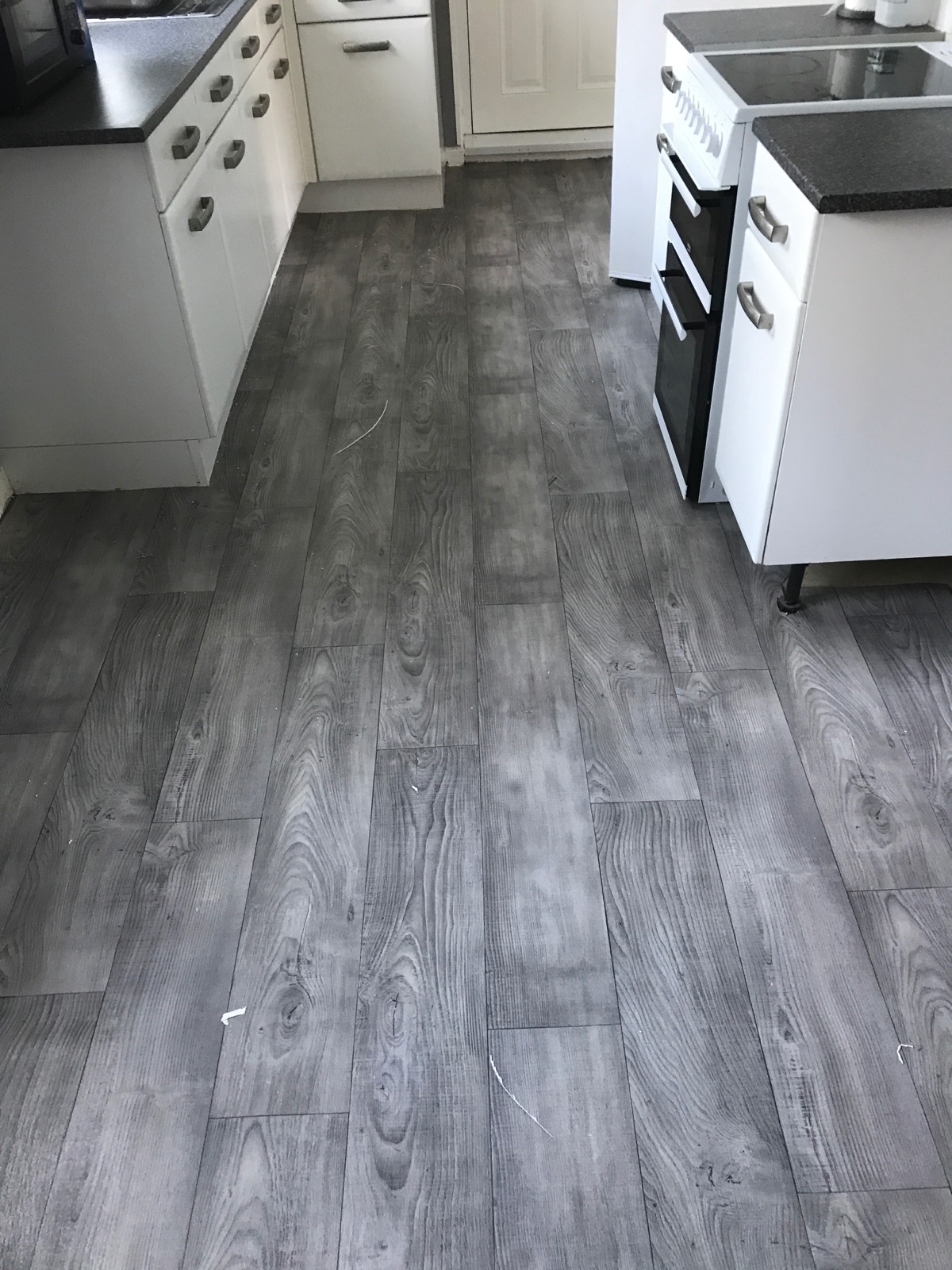 light grey vinyl flooring with laminate design in kitchen with white units