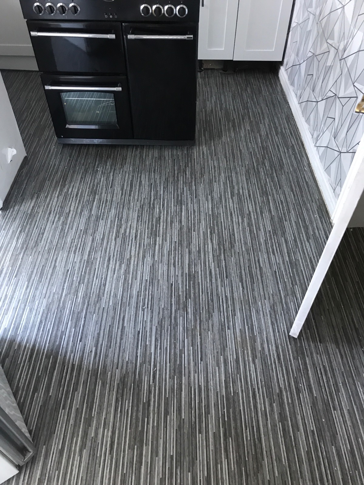 patterned grey vinyl flooring in kitchen with black oven 