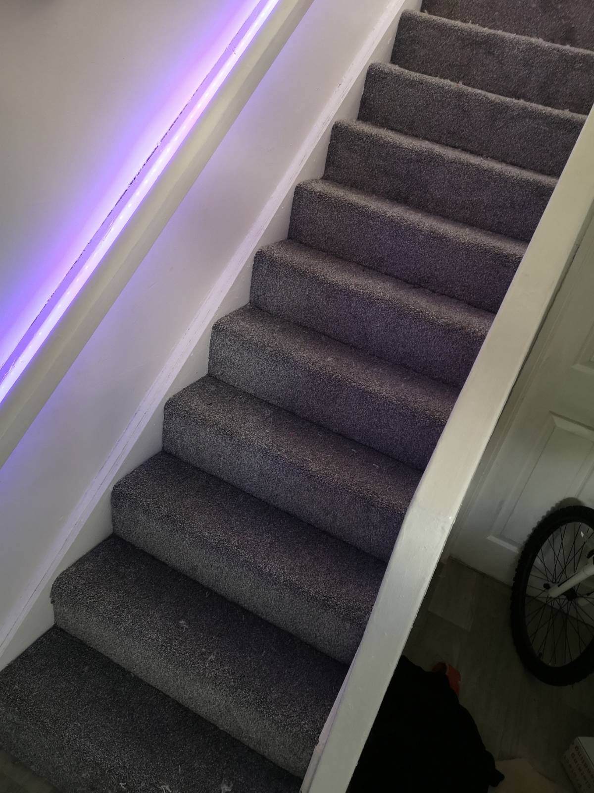 grey carpet fitting on staircase with purple lighting under banister
