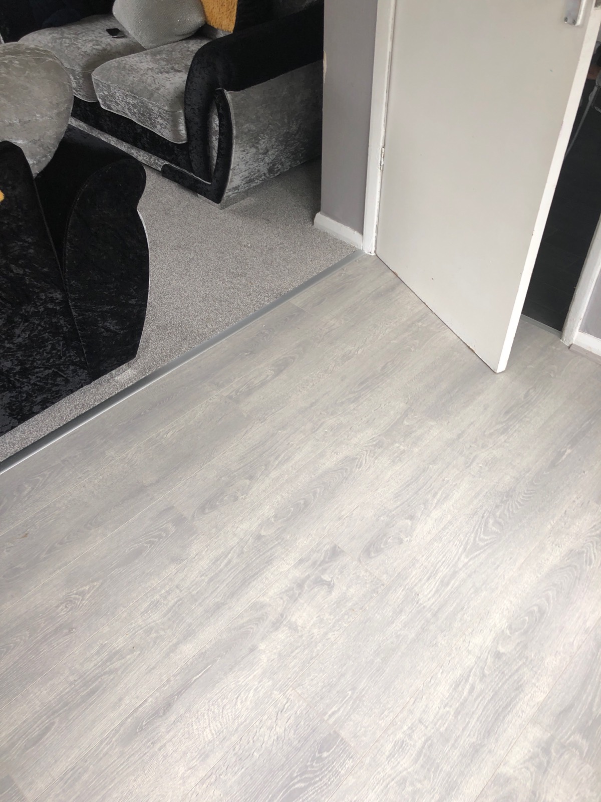 living room flooring split in half by grey laminate and grey carpet