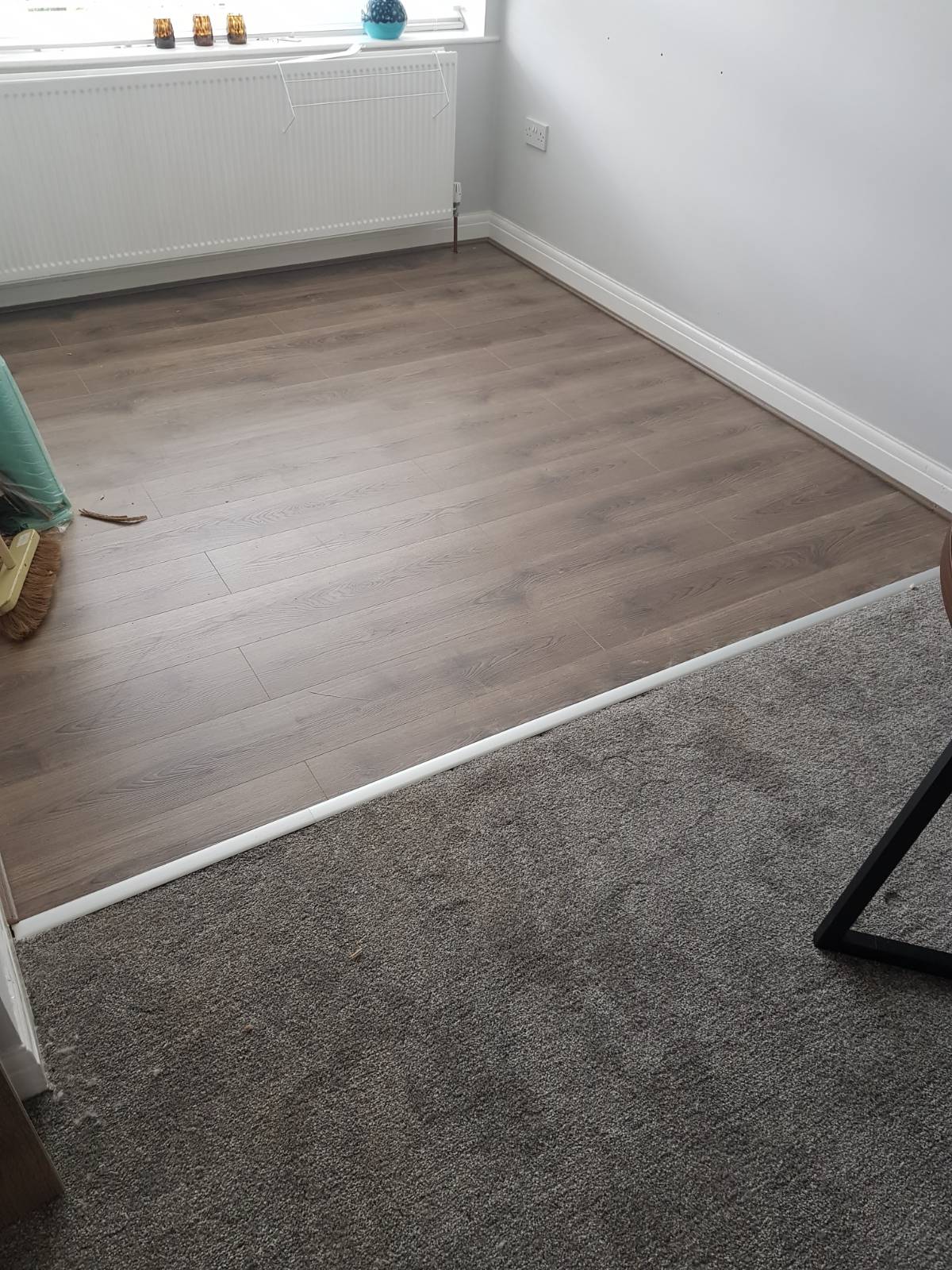 living room flooring split by half grey carpet and half brown laminate