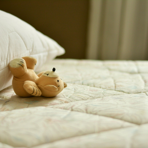 Teddy bear lying on bare mattress